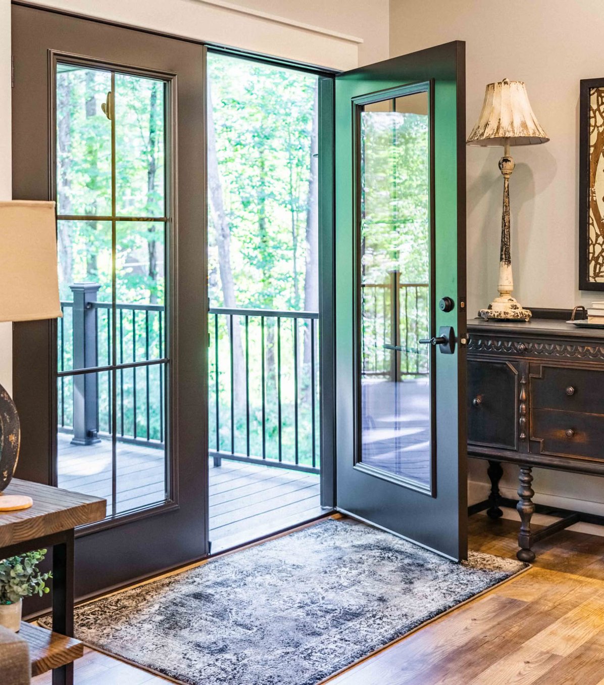 Green glass door opening to deck with metal railing.