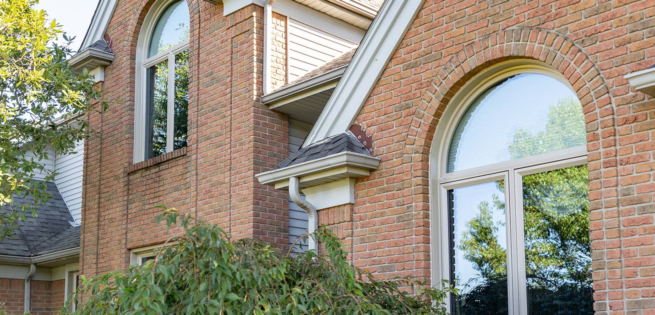 Red brick home exterior with white arched window frames.